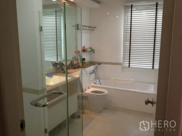 公寓 出租在Bang Rak, Bangkok - 现代化浴室，设玻璃淋浴房、浴缸、盥洗台与百叶窗。