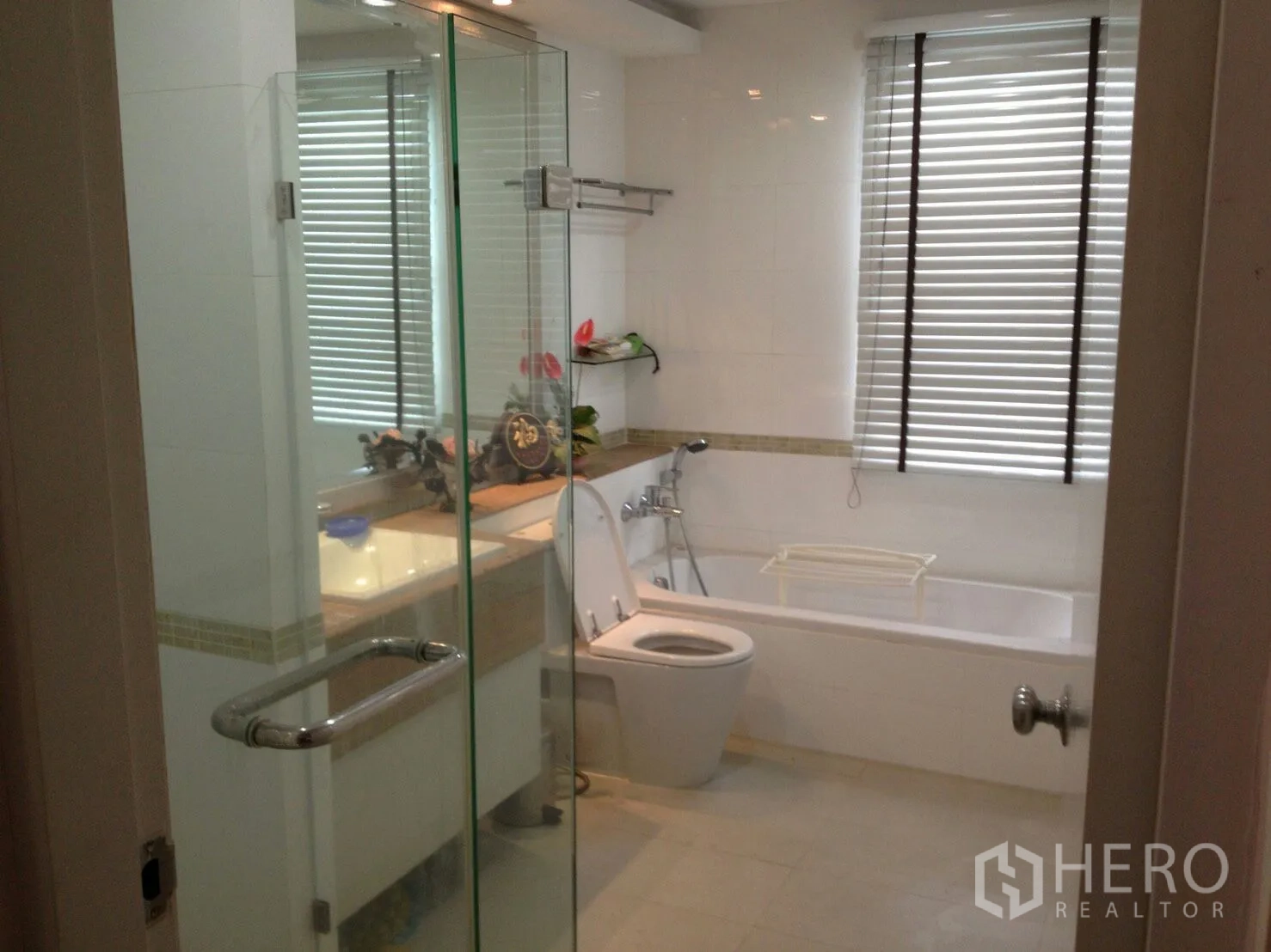 公寓 出租在Bang Rak, Bangkok - 现代化浴室，设玻璃淋浴房、浴缸、盥洗台与百叶窗。