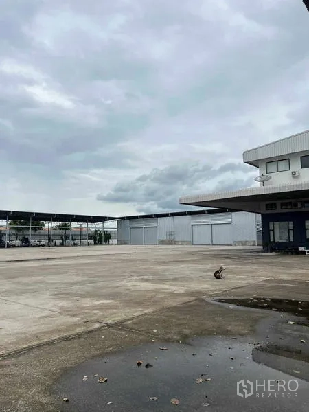 คลังสินค้า ให้เช่าในMueang Chon Buri, Chon Buri - ลานคอนกรีตกว้าง พร้อมด้านหน้าอาคารสำนักงานและโกดังหลายยูนิตในอำเภอเมืองชลบุรี ใต้ท้องฟ้าครึ้ม.