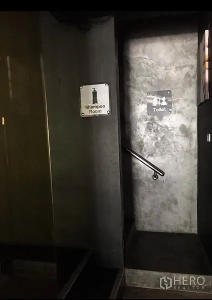 办公空间 出租在Pathum Wan, Bangkok - 室内楼梯与指示牌，通往卫生间的水泥墙通道。