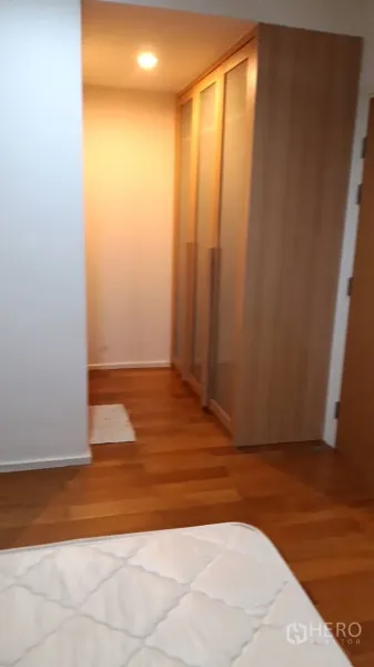 Condominium for rent in Watthana, Bangkok - Walk-in area with built-in wardrobes and warm lighting beside the bedroom.