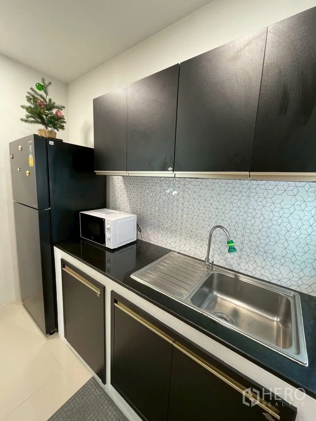 Detached House for rent in Prawet, Bangkok - Kitchen close-up with refrigerator, microwave, sink and dark cabinetry.