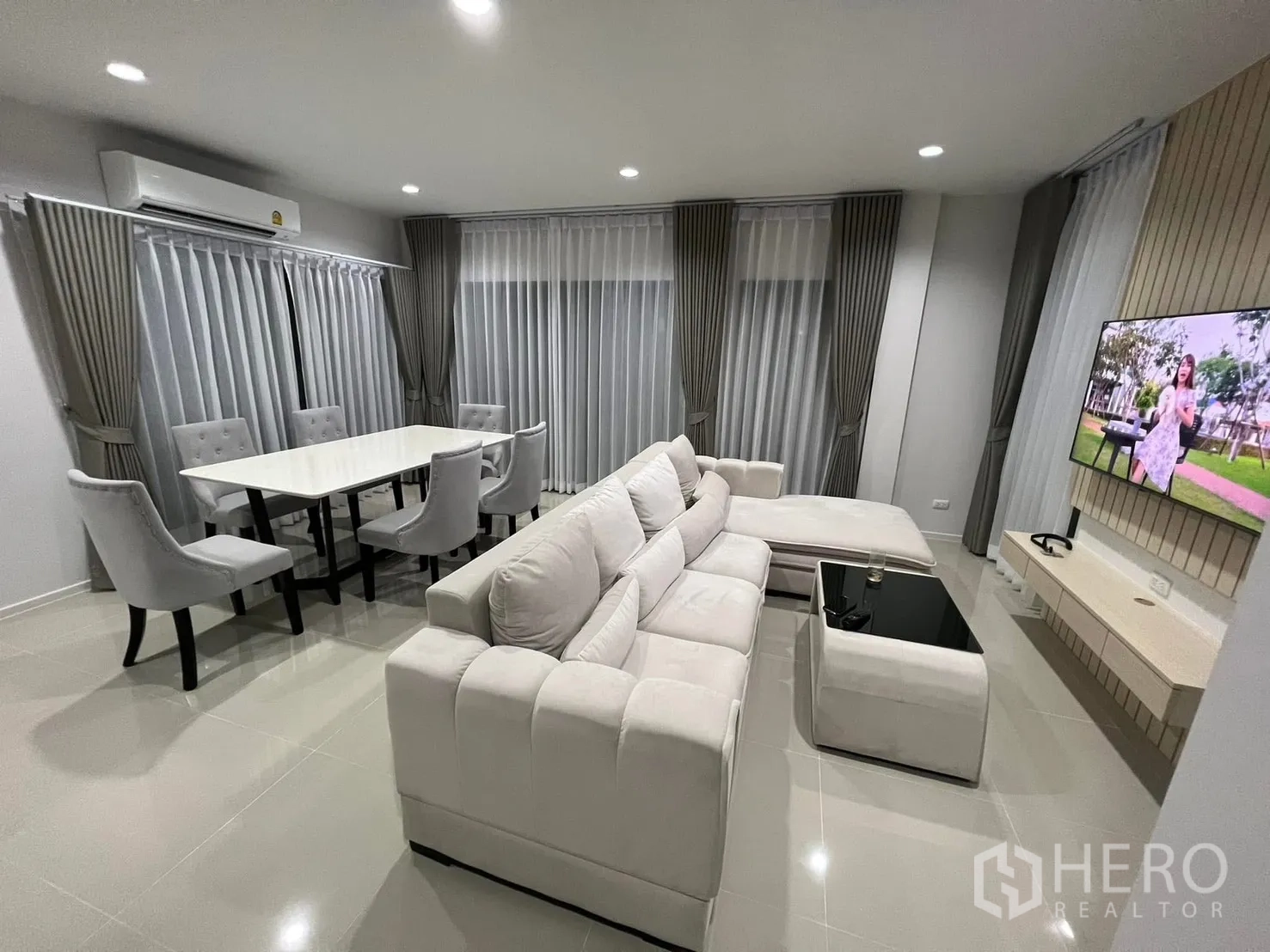 半独立式住宅 for rent in Saphan Sung, Bangkok - 开放式客餐厅，L形沙发、六人餐桌与落地窗帘。