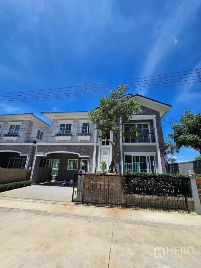 Detached House for rent in Thanyaburi, Pathum Thani - Modern two-storey detached house with driveway and front gate under a blue sky in Thanyaburi.