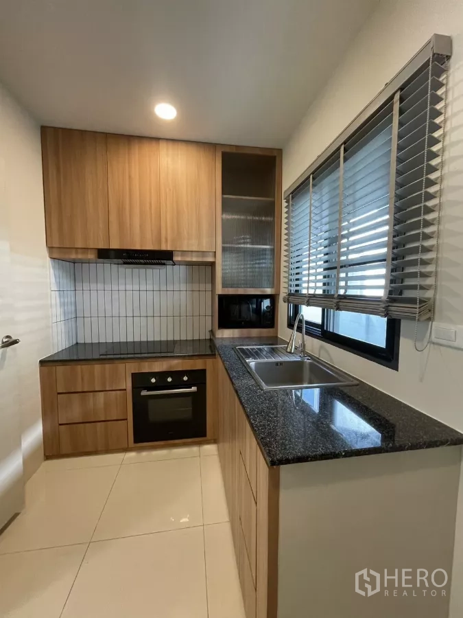 Detached House for rent in Bang Phli, Samut Prakan - Built-in kitchen with wood cabinets, black granite countertop, oven and tiled backsplash.