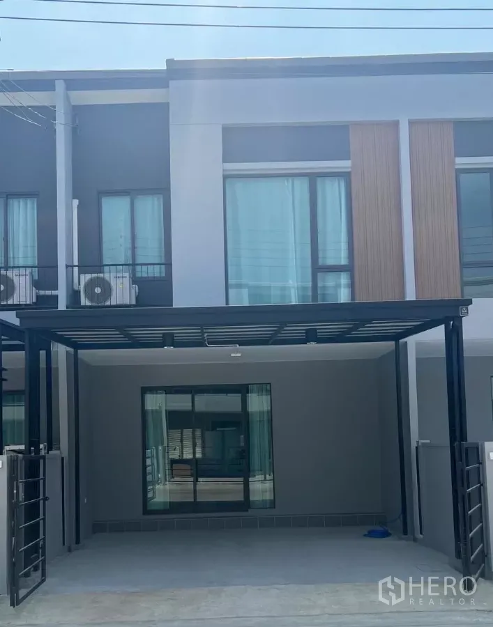 Townhouse for rent in Bang Phli, Samut Prakan - Modern two-storey townhouse facade with covered 2-car carport and large sliding glass doors.