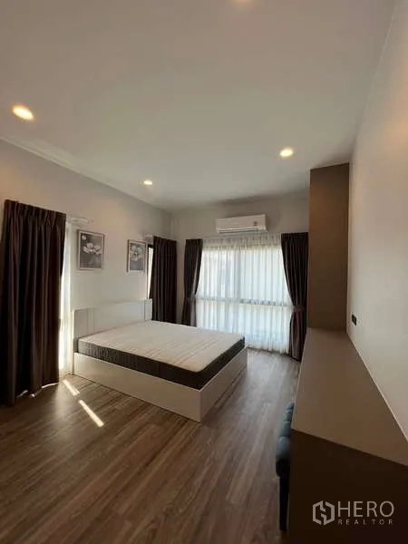 Detached House for rent in Bang Kapi, Bangkok - Sunlit bedroom with double bed, air-conditioning and sheer curtains.