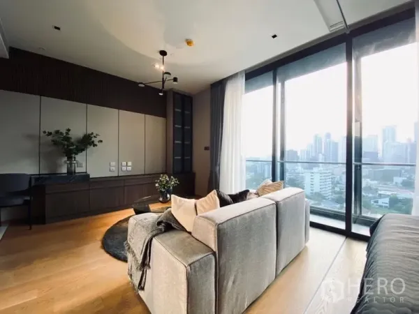 Condominium for sale - Sofa set by full-height glass doors opening to a balcony with Bangkok skyline views.