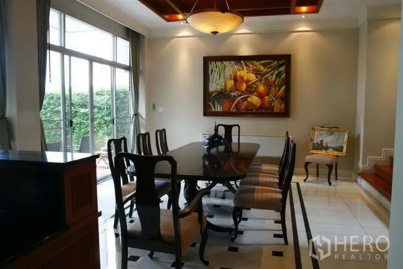 Detached House for rent in Phaya Thai, Bangkok - Formal dining room with long table, chandelier ceiling detail and sliding glass doors to the lawn.