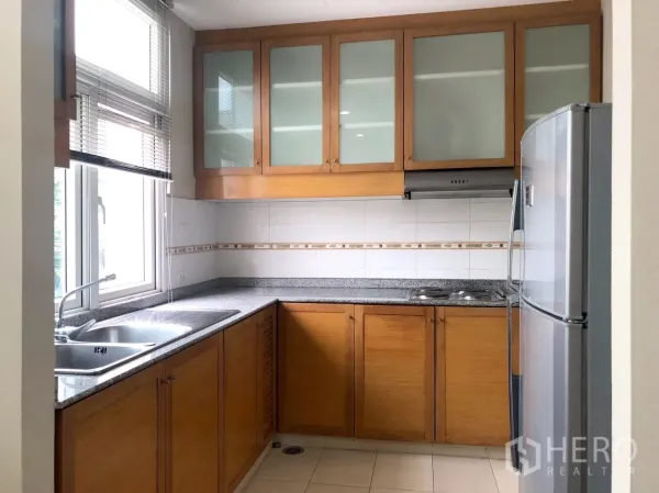 Apartment for rent in Khlong Toei, Bangkok - Bright closed kitchen with window, granite counters and wood cabinets