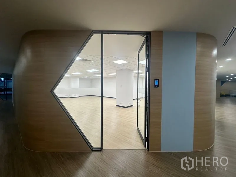 สำนักงาน ให้เช่าในChatuchak, Bangkok - ทางเข้าออฟฟิศสมัยใหม่ด้วยประตูกระจกทรงเรขาคณิตและผนังลายไม้โค้งมน