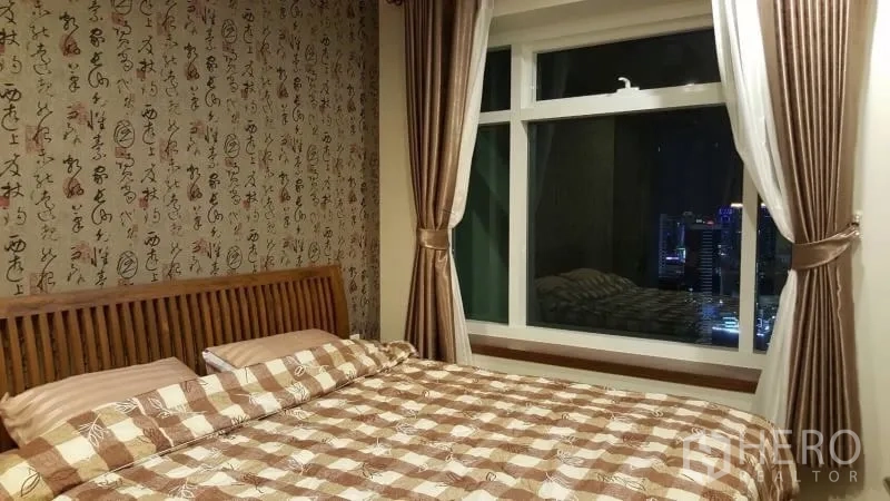 คอนโด ให้เช่าหรือขายในRatchathewi, Bangkok - ห้องนอนอบอุ่น เตียงไม้ วอลเปเปอร์ลวดลาย หน้าต่างบานใหญ่พร้อมวิวเมืองยามค่ำ