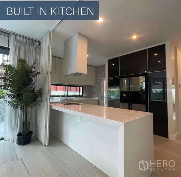 独立式住宅 出售在Khlong Toei, Bangkok - 现代一体化厨房，白色岛台与黑色橱柜电器。