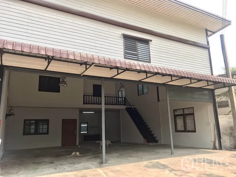 货栈 出租在Pathum Thani - 两层仓库立面，配有金属雨棚与覆盖式装卸区。