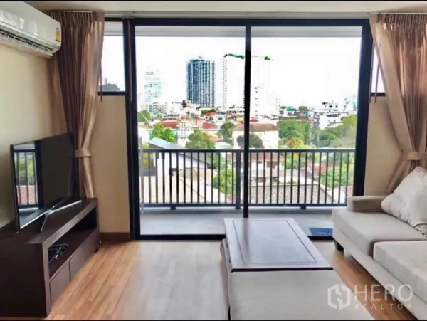 Condominium for rent in Watthana, Bangkok - Living area opening to a balcony with skyline view near BTS Ekkamai.