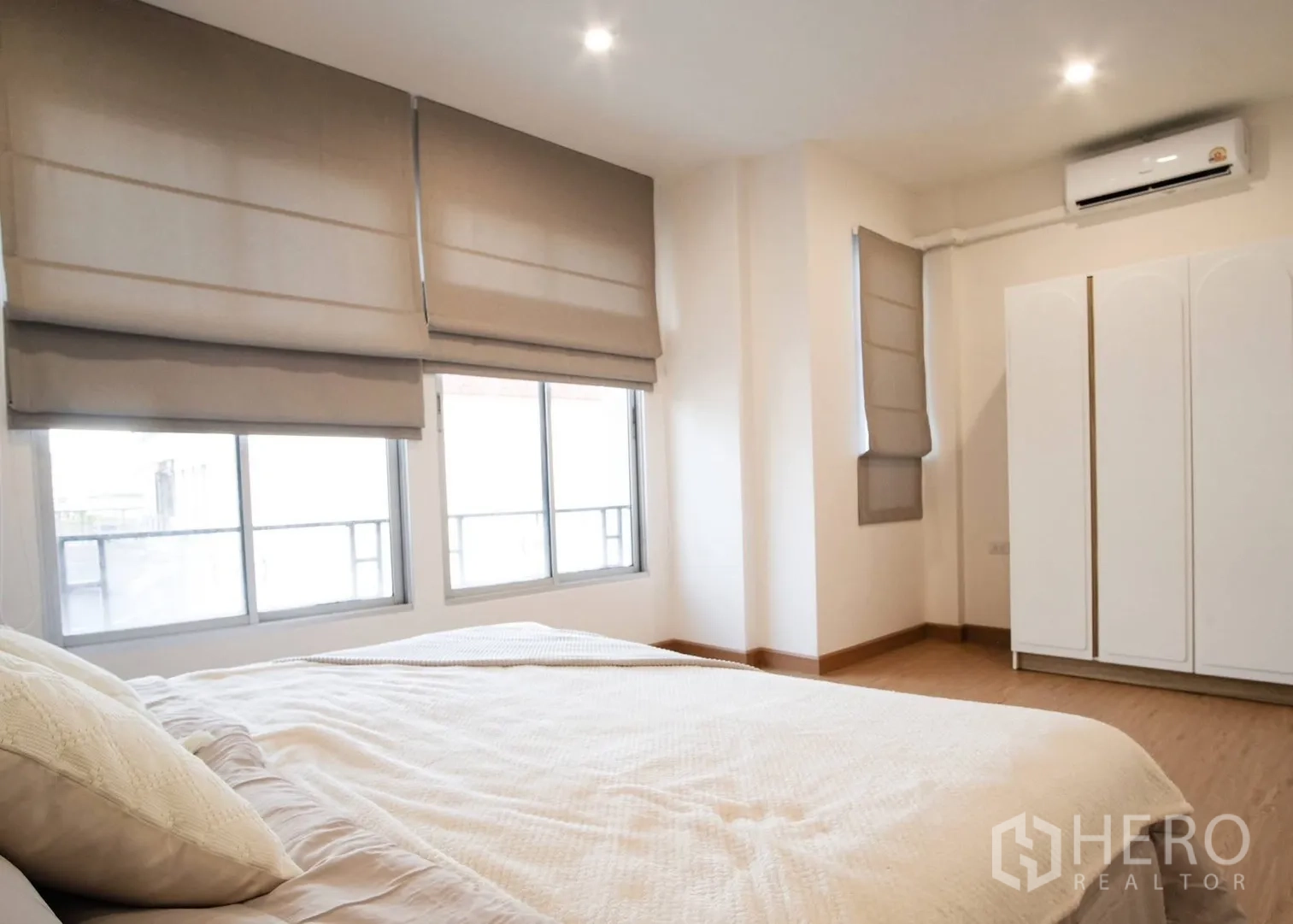 Townhouse for rent in Bang Phli, Samut Prakan - Sunlit bedroom with large windows, roman blinds, air conditioner, and white wardrobe.