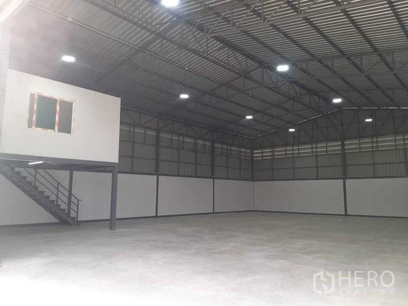 Warehouse for rent in Bang Khun Thian, Bangkok - Spacious high-ceiling warehouse interior with steel truss roof and bright lighting.