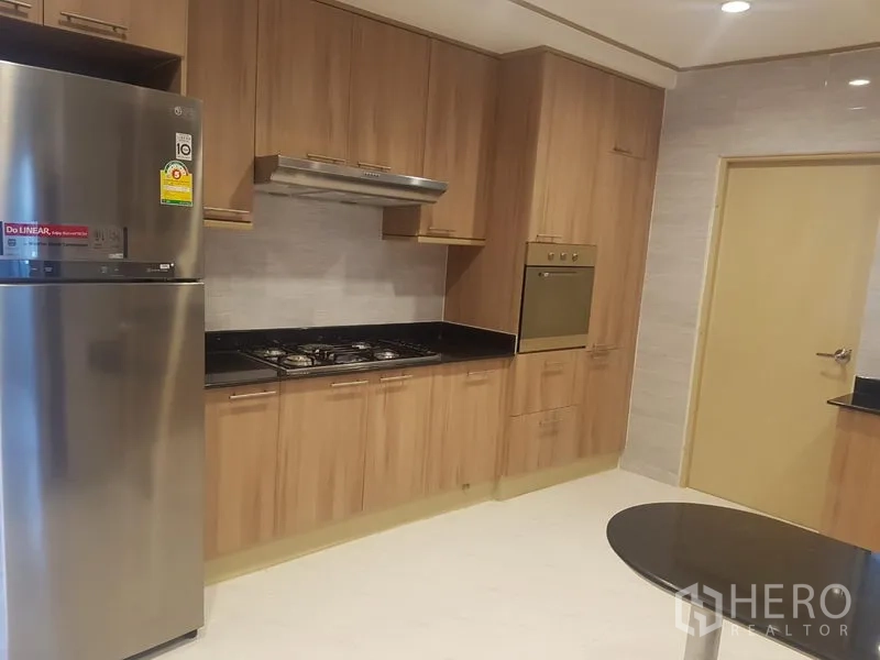 Apartment for rent in Khlong Toei, Bangkok - Modern kitchen with gas hob, stainless fridge, oven and wood cabinets