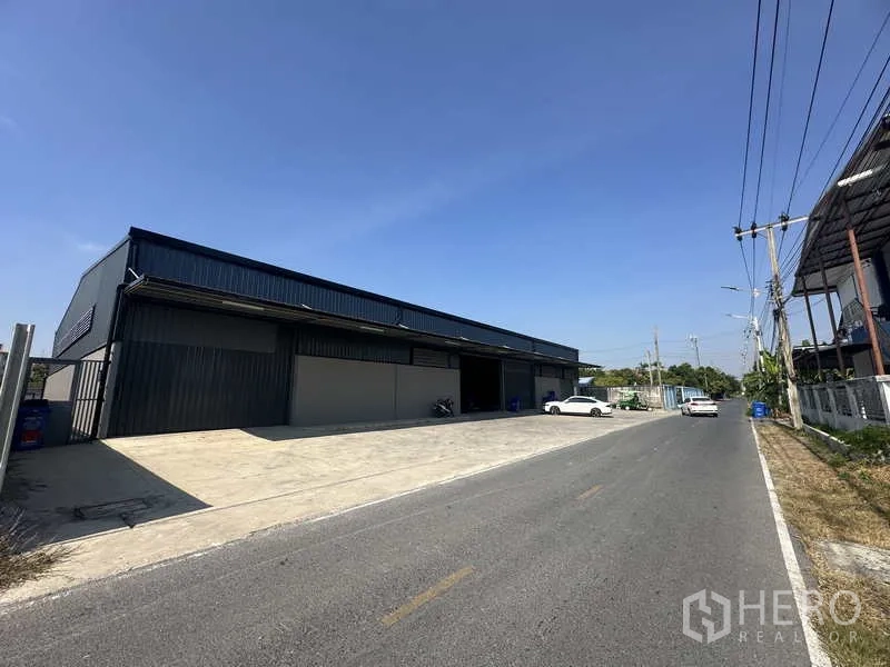 Warehouse for rent in Bang Bua Thong, Nonthaburi - Street view showing the warehouse frontage and a wide access road suitable for trucks.
