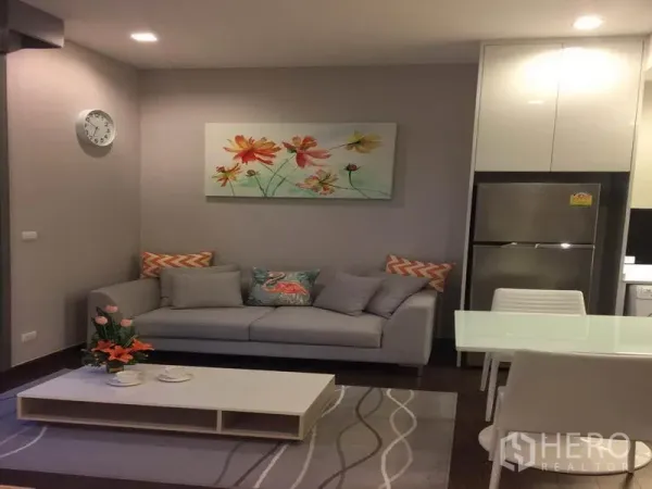 คอนโด ให้เช่าในRatchathewi, Bangkok - มุมนั่งเล่นอบอุ่น โซฟาสีเทา โต๊ะกลาง ชุดโต๊ะทานอาหาร แสงไฟดาวน์ไลท์นุ่มนวล