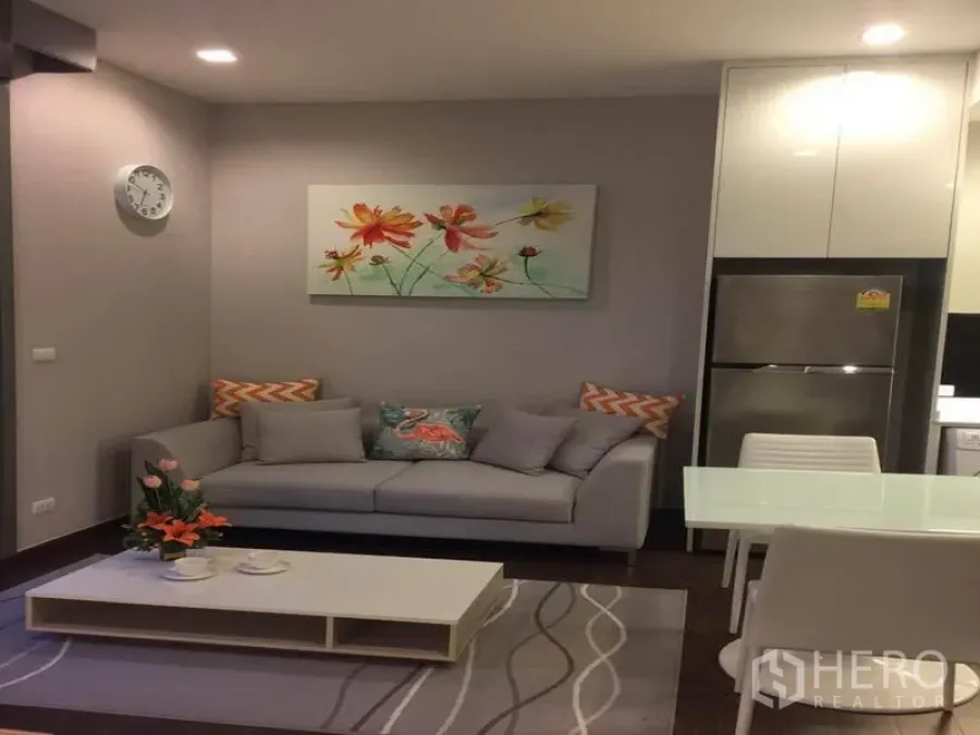 คอนโด ให้เช่าในRatchathewi, Bangkok - มุมนั่งเล่นอบอุ่น โซฟาสีเทา โต๊ะกลาง ชุดโต๊ะทานอาหาร แสงไฟดาวน์ไลท์นุ่มนวล