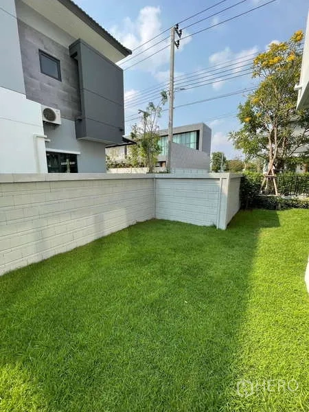Detached House for rent in Bang Phli, Samut Prakan - Corner lawn garden enclosed by a low white wall.