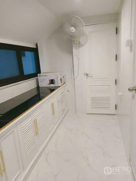 Condominium for  in Watthana, Bangkok - Utility corridor of the kitchen with storage cabinets and wall fan.