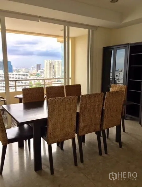 Condominium for rent in Watthana, Bangkok - Dining area with woven chairs opening to a balcony and wide Bangkok skyline view.
