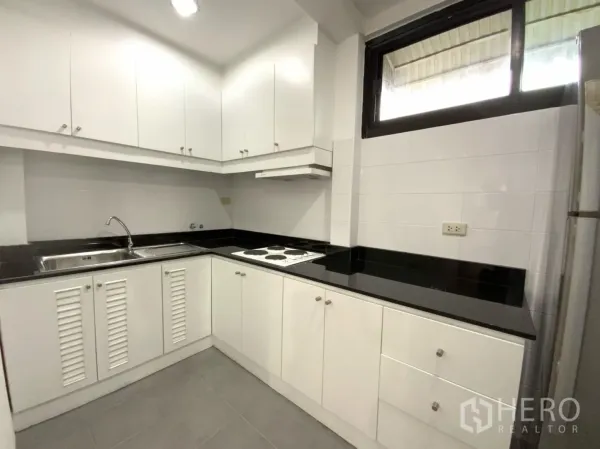 คอนโด ให้เช่าในWatthana, Bangkok - ครัวรูปตัว U ตู้สีขาว ท็อปสีดำ เตาไฟฟ้า เครื่องดูดควัน และอ่างล้างจาน