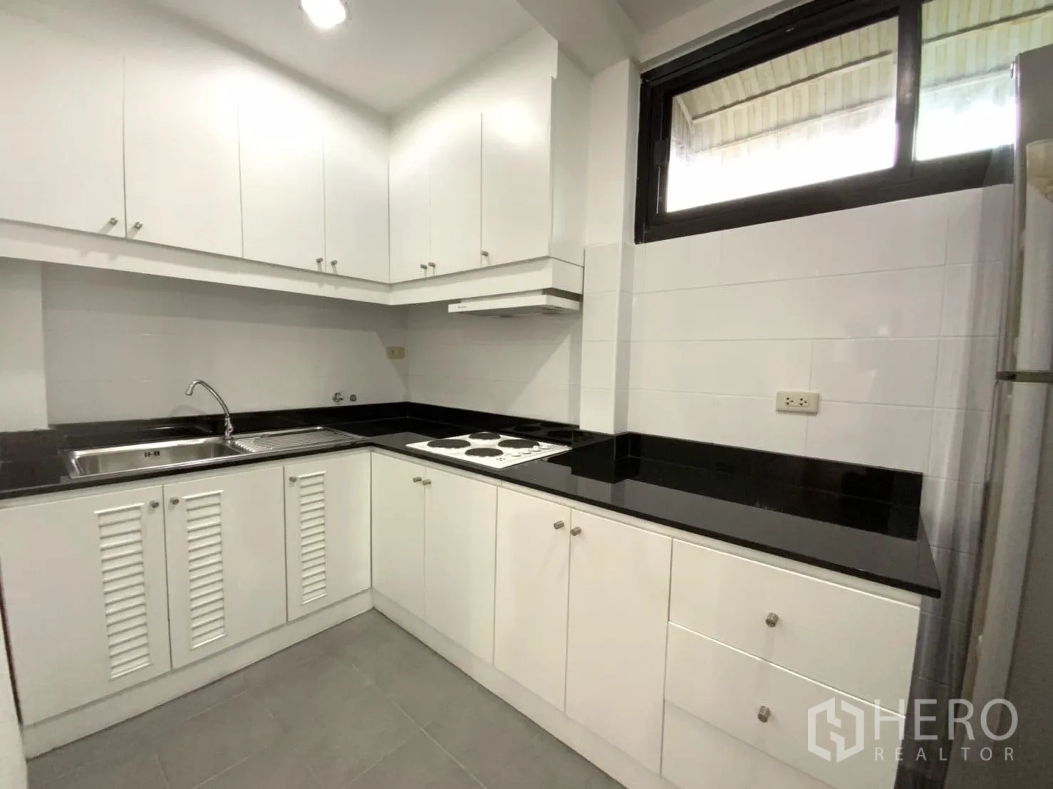 คอนโด ให้เช่าในWatthana, Bangkok - ครัวรูปตัว U ตู้สีขาว ท็อปสีดำ เตาไฟฟ้า เครื่องดูดควัน และอ่างล้างจาน