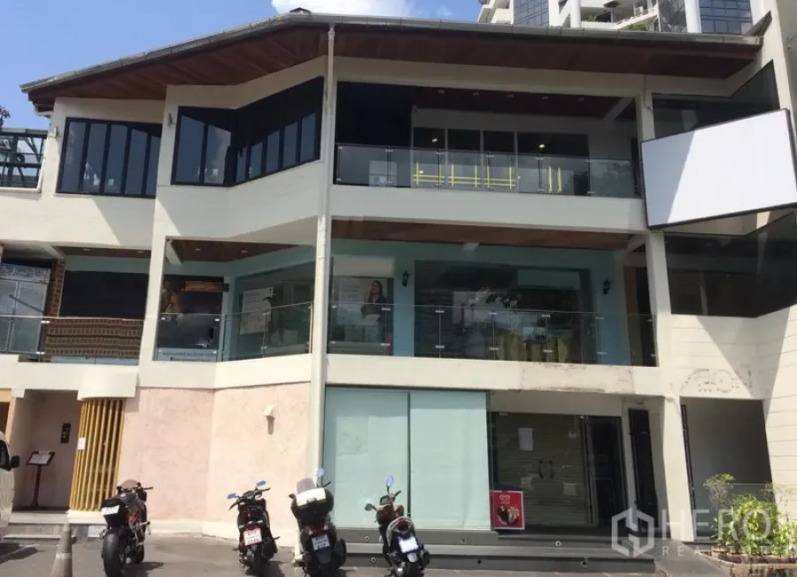 零售空间 出租在Watthana, Bangkok - 通罗瓦他那区现代多层商业楼外观，玻璃立面与阳台，显眼招牌位，门前有摩托车停放
