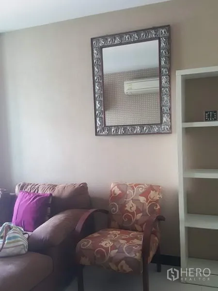 คอนโด ให้เช่าในKhlong Toei, Bangkok - มุมห้องนั่งเล่นมีเก้าอี้ลายดอก โซฟา กระจกติดผนัง และชั้นวางในตัว