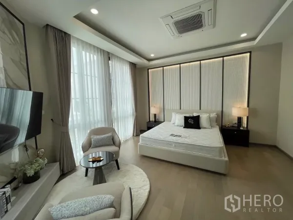 Detached House for rent in Lat Phrao, Bangkok - Spacious master bedroom with large windows, king bed and a cozy seating corner.