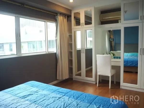 Condominium for rent or sale in Watthana, Bangkok - Bedroom corner with mirrored built-in wardrobes and a dressing table by the window.