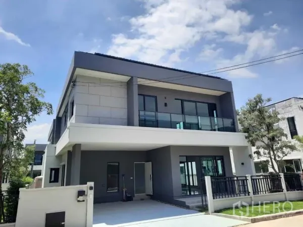 Detached House for rent in Bang Phli, Samut Prakan - Modern two-storey detached house with glass balcony and driveway under a blue sky.