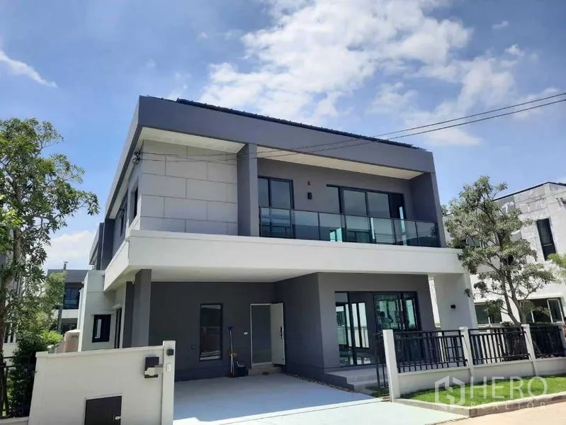 Detached House for rent in Bang Phli, Samut Prakan - Modern two-storey detached house with glass balcony and driveway under a blue sky.