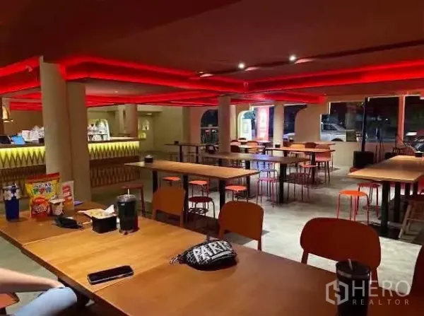 พื้นที่ขายปลีก ให้เช่าในSathon, Bangkok - โถงรับประทานชั้นล่าง โต๊ะไม้ยาว เพดานไฟแดง และที่นั่งแบบโอเพ่นแพลน
