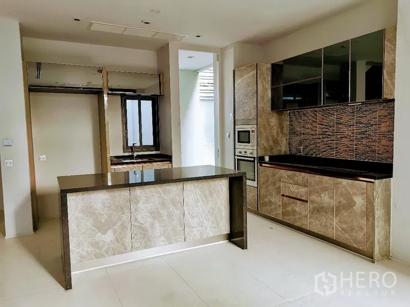 Detached House for sale in Wang Thonglang, Bangkok - Fitted kitchen from another angle showing marble-look cabinetry and a central island.