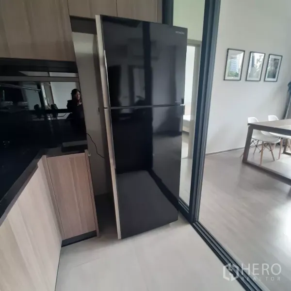 คอนโด ให้เช่าในWatthana, Bangkok - ครัวบิวท์อินพร้อมตู้เย็นสีดำและตู้ไม้ ถัดจากประตูกระจกบานเลื่อนไปยังโซนทานข้าว