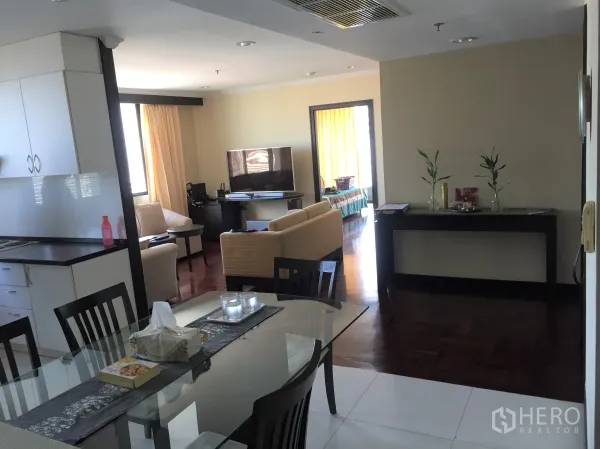 Condominium for rent or sale in Khlong Toei, Bangkok - Open-plan dining area leading to living room with TV and sofas in a Bangkok condominium.