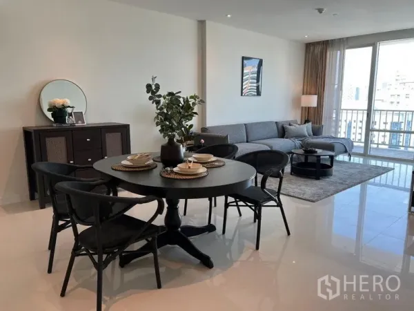Condominium for rent in Watthana, Bangkok - Open-plan living and dining room with gray sectional, round black dining set and floor-to-ceiling windows overlooking Bangkok.