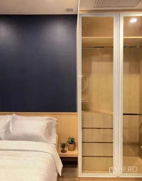 คอนโด ให้เช่าในWatthana, Bangkok - มุมห้องนอนพร้อมชุดเครื่องนอนสีขาว ตู้เสื้อผ้าบานเลื่อนกระจก และผนังสีน้ำเงิน