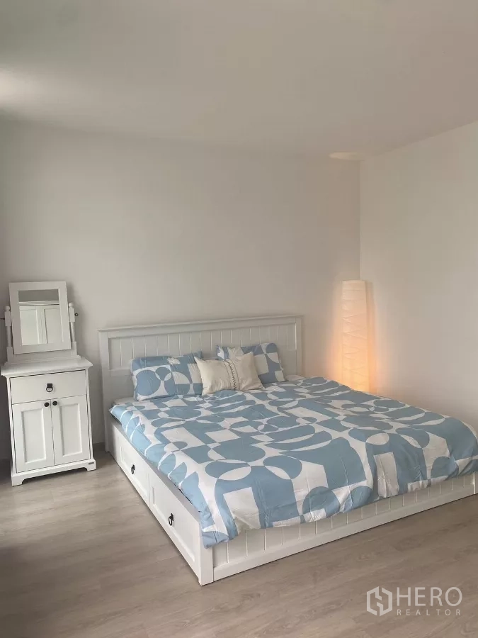 联排别墅 出租在Prawet, Bangkok - 温馨卧室，蓝色几何床品与落地灯。