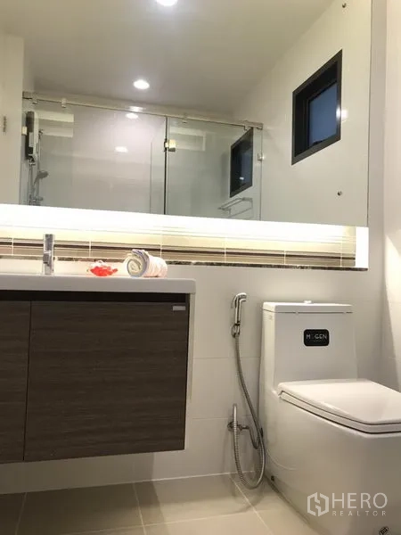 Detached House for rent in Bang Kapi, Bangkok - Modern bathroom with glass shower enclosure, vanity cabinet and toilet with bidet spray.