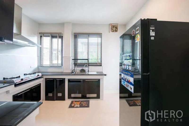 独立式住宅 出租或出售在Kanchanaburi - 现代厨房，黑色橱柜，燃气灶、油烟机与大冰箱。