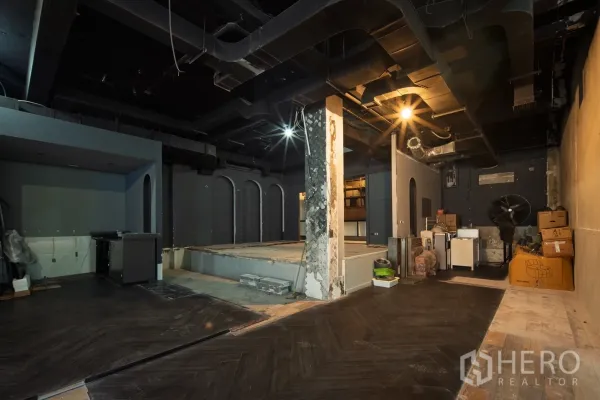 零售空间 出租在Watthana, Bangkok - 宽敞空间，外露黑色天花、抬高平台与临时储物区。