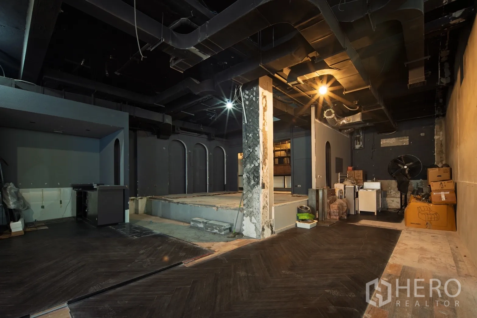 零售空间 出租在Watthana, Bangkok - 宽敞空间，外露黑色天花、抬高平台与临时储物区。