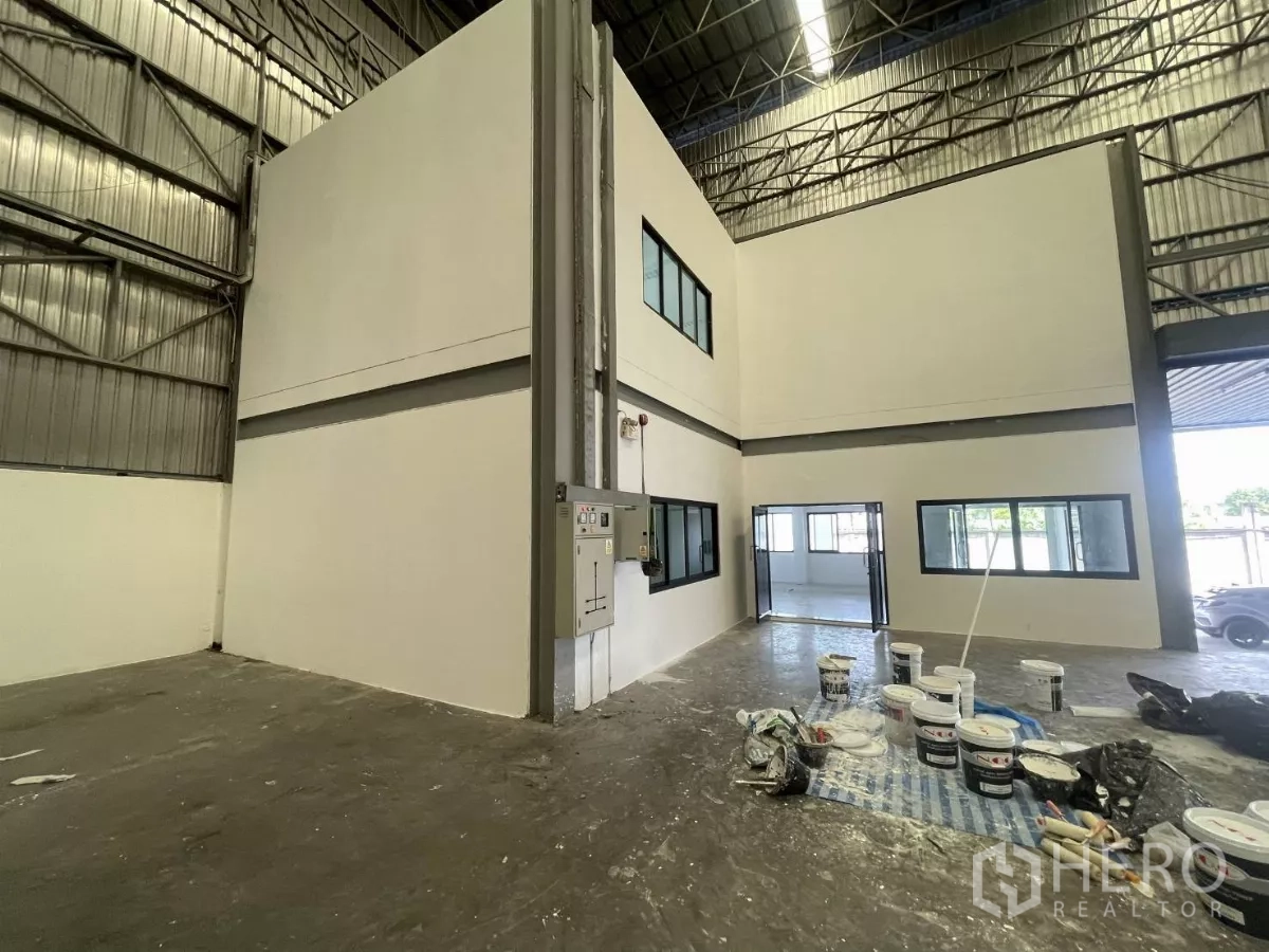 Warehouse for rent in Lat Krabang, Bangkok - Two-storey office core under renovation with windows and paint supplies.