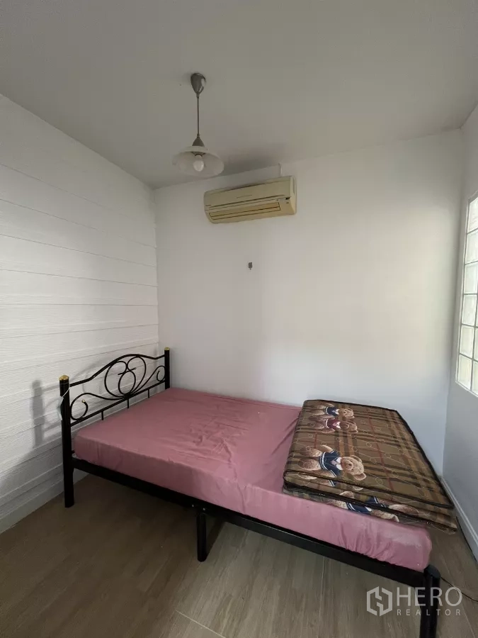 Detached House for rent in Bang Kapi, Bangkok - Compact ground-floor bedroom with metal bedframe and air-conditioner.