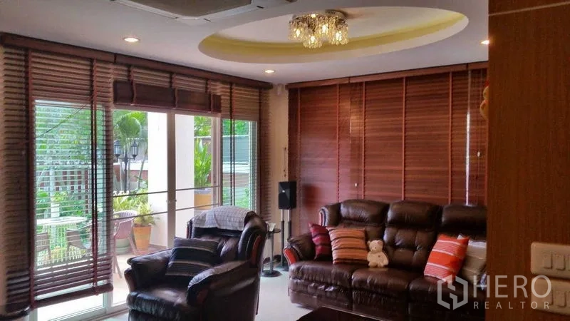 Detached House for sale in Suan Luang, Bangkok - Bright lounge with sliding glass doors, wood blinds, and ceiling chandelier.